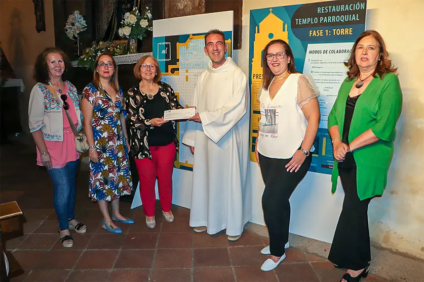 Integrantes de AFAMMER, junto al párroco de Almodóvar del Campo, efectuando la entrega del cheque por el importe donado